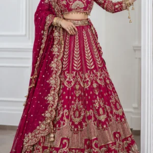 Maroon Bridal Lehenga with Heavy Gold Embroidery Make a regal statement on your special occasion with Maroon Bridal Lehenga with Heavy Gold Embroidery , a luxurious wine maroon bridal lehenga designed for women who appreciate traditional Indian craftsmanship, elaborate embroidery, and timeless bridal elegance. This breathtaking designer lehenga features a deep wine-maroon base enriched with intricate gold-toned embroidery, an ornate full-sleeved blouse, a beautifully flared lehenga skirt, and a matching embellished dupatta. The rich jewel-toned colour creates an instantly luxurious appearance, while the extensive embroidery adds depth, grandeur, and sophistication. The ensemble showcases elaborate botanical and floral-inspired motifs arranged throughout the blouse, skirt, borders, and dupatta. Intricate leafy patterns, ornamental flourishes, traditional motifs, and detailed borders create a richly layered visual effect. The blouse features a graceful neckline, fitted silhouette, and full sleeves decorated with coordinated embroidery. The lehenga skirt opens into a dramatic flare, with vertical leafy motifs and elaborate ornamental patterns flowing down the fabric. Multiple heavily embroidered borders complete the hem, giving the skirt a regal and couture-inspired finish. The matching wine-maroon dupatta adds another layer of luxury. Its ornate gold border, scattered embellishments, and intricate decorative motifs complement the lehenga beautifully. Created for brides, close family members, and women attending grand celebrations, Ruhani Gulab is an ideal choice for weddings, receptions, engagement ceremonies, sangeet celebrations, and formal Indian occasions. A Rich Wine-Maroon Colour The deep wine-maroon shade is the foundation of this ensemble and gives it its powerful bridal character. Maroon and wine tones have long been associated with luxury, celebration, sophistication, and traditional Indian bridal fashion. Compared with brighter reds, a deep wine-maroon shade offers a more mature and dramatic interpretation of bridal dressing. The rich colour creates a beautiful background for the gold embroidery. Every gold motif becomes more prominent against the deep base, allowing the intricate craftsmanship to remain visible from both a distance and up close. This colour palette is particularly beautiful for evening weddings and receptions, where warm lighting enhances the depth of the maroon fabric and allows the gold detailing to create a luminous effect. For brides who want a traditional bridal colour with a sophisticated contemporary personality, wine maroon offers an elegant alternative to classic bright red. Heavily Embroidered Designer Blouse The blouse is one of the most striking components of the ensemble. Designed in the same deep wine-maroon shade as the lehenga, the blouse is covered with intricate gold-toned embroidery. The neckline features elaborate floral and ornamental detailing that creates a beautiful frame around the face and neck. The embroidery extends naturally across the bodice, creating a richly decorated appearance. A central ornamental motif adds definition to the front of the blouse, while surrounding floral and leafy patterns create balance. The full sleeves are also heavily embroidered, continuing the same design language from the bodice. This creates a seamless appearance from the neckline to the cuffs. The fitted blouse provides structure against the flowing volume of the lehenga skirt, creating a balanced bridal silhouette. The combination of a fitted embroidered blouse and dramatically flared skirt gives the ensemble a classic couture-inspired appearance. Elegant Full-Sleeved Silhouette The full sleeves give this bridal blouse a sophisticated and timeless character. Instead of using a heavily embellished sleeveless or short-sleeved design, the long sleeves create a more regal appearance. The embroidery extends throughout the sleeves, with ornate floral motifs and delicate decorative elements placed across the fabric. This makes the blouse particularly attractive in close-up photographs. The sleeves also work beautifully with traditional bridal jewellery, including bangles, bracelets, and statement rings. The full-sleeved design can create an elegant and polished appearance for winter weddings, formal receptions, and grand evening celebrations. Intricate Gold Embroidery Gold embroidery is the visual language that connects the entire ensemble. The design incorporates multiple layers of ornamental detailing rather than relying on one repeated motif. Floral patterns, leaves, scrolling vines, traditional decorative elements, and geometric-inspired borders are carefully arranged throughout the lehenga. The embroidery becomes increasingly elaborate toward the lower portion of the skirt. This creates a beautiful sense of progression. The upper section features vertically arranged motifs that elongate the silhouette, while the lower portion becomes richer with multiple layers of ornate borders. This approach gives the lehenga a sophisticated couture appearance and ensures that every section of the outfit contributes to the overall design. Statement Lehenga Skirt The lehenga skirt is the centrepiece of Ruhani Gulab. Its full, flowing silhouette creates dramatic volume and movement. The deep wine-maroon fabric provides a rich foundation for the extensive gold embroidery. One of the most distinctive details is the arrangement of elongated leafy motifs running vertically across the upper and middle sections of the skirt. These motifs create a flattering visual direction and help emphasise the length of the silhouette. Between the larger motifs, smaller floral and ornamental details add texture. As the eye moves downward, the embroidery becomes progressively more elaborate. This creates a beautifully decorated lower section that gives the skirt a regal and luxurious appearance. Elaborate Multi-Layered Hem The hemline is one of the most heavily decorated sections of the lehenga. Several layers of gold embroidery create a broad, statement border around the bottom. Floral and lotus-inspired motifs appear alongside scrolling ornamental patterns, creating a traditional Indian aesthetic. Additional geometric and patterned borders add definition between the different sections. The multiple layers of embroidery create a strong finishing line around the skirt and give the lehenga a beautifully structured appearance. When the skirt moves, the decorated hem catches attention and creates a dramatic visual effect. This makes the lehenga especially suitable for bridal entrances, stage photographs, full-length portraits, and wedding ceremonies. Ornate Wine-Maroon Dupatta The matching dupatta completes the ensemble. Designed in the same rich wine-maroon tone, the dupatta creates a cohesive look from head to toe. Its border is heavily decorated with intricate gold embroidery. Floral and ornamental motifs extend along the border, creating a beautiful frame around the fabric. Scattered embellishments across the body of the dupatta add additional sparkle and ensure that it does not appear plain when draped. The dupatta can be styled traditionally over the head for a bridal ceremony or draped over one shoulder for a contemporary reception look. Its ornate border becomes especially prominent when arranged across the front of the body. Traditional Bridal Aesthetic Ruhani Gulab embraces the timeless language of Indian bridal fashion. Rich colour. Gold embroidery. A full flared lehenga. A heavily embellished blouse. A statement dupatta. Together, these elements create a bridal ensemble with a strong traditional identity. At the same time, the detailed placement of the embroidery and structured silhouette give the design a contemporary couture feel. This balance makes the outfit appropriate for brides who want traditional Indian wedding clothing without sacrificing modern sophistication. Perfect for Bridal Weddings This designer lehenga is particularly suited to bridal celebrations. Its rich wine-maroon colour and elaborate gold detailing create the grandeur expected from a bridal ensemble. It can be styled for: Wedding ceremonies Bridal receptions Engagement celebrations Sangeet functions Pre-wedding celebrations Formal wedding dinners Destination weddings Family wedding events Traditional ceremonies Luxury receptions For the bride, the outfit can be paired with elaborate jewellery and a traditional dupatta drape. For a close family member, the jewellery can be kept lighter to create a sophisticated formal look. Ideal for Evening Weddings The deep maroon and gold colour combination is particularly effective for evening events. Under warm wedding lighting, the gold embroidery can create a luminous appearance against the dark base. This makes the ensemble an excellent choice for evening wedding ceremonies, receptions, and formal celebrations. For evening styling, pair it with statement jewellery, a metallic clutch, and a polished hairstyle. The result is a dramatic yet elegant bridal appearance. Engagement and Reception Styling Although the ensemble has a bridal character, it can also be styled beautifully for an engagement or reception. For an engagement, choose a sophisticated choker, large earrings, and a sleek hairstyle. For a reception, statement jewellery and a glamorous makeup look can enhance the richness of the maroon and gold palette. If you want a more contemporary appearance, wear the dupatta over one shoulder and allow the blouse embroidery to remain clearly visible. Jewellery Styling The richness of the outfit provides the perfect foundation for traditional bridal jewellery. For a classic bridal appearance, pair the lehenga with: A statement choker Long layered necklace Traditional jhumkas Maang tikka Nath Bangles Bridal rings Gold-toned jewellery complements the embroidery naturally. Kundan-inspired, polki-inspired, or antique-finish jewellery can also create a regal appearance. For a more contemporary reception look, choose one statement choker with large earrings and keep the remaining jewellery minimal. Hairstyle Suggestions A traditional centre-parted bun is an excellent choice for this lehenga. The bun can be decorated with fresh flowers, traditional hair accessories, or jewellery. This hairstyle works particularly well with a maang tikka and keeps the neckline and earrings visible. For a more contemporary reception look, soft waves or a polished low bun can create an elegant contrast with the heavily embroidered outfit. If the dupatta is styled over the head, a neat bun provides a clean and balanced foundation. Makeup Suggestions The deep wine-maroon colour pairs beautifully with warm and glamorous makeup. For the eyes, choose gold, bronze, champagne, or warm brown tones. Defined eyeliner and softly sculpted brows can enhance the traditional bridal appearance. A luminous complexion works beautifully with the reflective quality of gold embroidery. For the lips, choose a deep rose, berry, wine, classic red, or muted nude depending on the desired intensity. For a traditional bridal look, a deeper lip can complement the rich colour of the lehenga. For a contemporary reception look, a softer rose or nude lip can create more balance. Perfect for Sangeet Celebrations The full lehenga silhouette creates beautiful movement, making it suitable for sangeet celebrations. The flared skirt can move gracefully while walking, posing, and dancing. For a sangeet, the dupatta can be draped securely over one shoulder. Pair it with statement earrings, a sleek hairstyle, and glamorous makeup for a sophisticated evening look. The gold embroidery will also photograph beautifully under event lighting. Destination Wedding Appeal The deep wine-maroon palette works beautifully against heritage architecture and luxurious wedding venues. Whether the wedding is held in a palace, heritage haveli, luxury hotel, resort, or traditional venue, the rich colour and gold detailing can create a dramatic visual effect. For destination weddings, style the outfit with traditional jewellery and a structured clutch. The flowing skirt can also create beautiful movement in outdoor photographs. Photography-Friendly Design Every element of the lehenga contributes to its photographic appeal. The rich maroon base creates a dramatic foundation. The gold embroidery adds texture. The vertical leafy motifs create visual length. The elaborate hem creates a strong finishing line. The embroidered blouse provides detailed close-up moments. The ornate dupatta adds movement and another layer of visual interest. This makes the ensemble particularly suitable for bridal portraits, wedding entrances, family photographs, couple photographs, and reception photography. A Regal Silhouette for the Modern Bride Modern bridal fashion increasingly combines traditional craftsmanship with contemporary styling. Ruhani Gulab reflects this evolution. The design retains the classic elements of Indian bridal wear while using carefully arranged embroidery to create a polished and sophisticated appearance. The fitted blouse defines the upper body, while the flowing lehenga creates volume. The result is a balanced silhouette that feels feminine, elegant, and regal. Suitable for Close Family Members Although this design can make a beautiful bridal lehenga, it can also be styled for close family members. A bride's sister, cousin, sister-in-law, or close family member can wear the ensemble for a formal wedding celebration. By reducing the jewellery and choosing a softer makeup look, the same outfit can become an elegant family-wedding ensemble. This versatility makes it suitable for women looking for luxurious Indian occasion wear beyond bridal dressing. Custom-Made Designer Lehenga At Maharani Designer Boutique, selected bridal and occasion-wear designs may be customised or made to measure according to individual requirements. Customers can discuss measurements, blouse fitting, neckline preferences, sleeve requirements, dupatta styling, and other possible design adjustments depending on the selected product. If you are ordering the outfit for a wedding, sharing the event date in advance is recommended. Heavily embroidered bridal garments require careful craftsmanship, construction, and finishing, so production timelines may vary depending on the design and level of customisation. A Timeless Bridal Investment A bridal lehenga often becomes more than just clothing. It becomes part of the memories, photographs, celebrations, and traditions associated with one of life's most important occasions. The rich wine-maroon and gold colour combination has a timeless quality that can remain beautiful long after current fashion trends change. The traditional motifs and ornate borders also give the outfit a classic character. With careful storage and professional cleaning, an elaborate designer lehenga can remain a treasured part of an occasion-wear wardrobe. Indian Luxury Fashion Luxury Indian clothing is defined by its craftsmanship, detailing, colour, and finishing. This ensemble brings those elements together through elaborate embroidery, a rich colour palette, a dramatic silhouette, and a coordinated dupatta. The extensive embroidery creates visual richness without requiring additional accessories to make the outfit feel complete. Jewellery can enhance the appearance, but the lehenga itself remains the primary statement piece. Care and Storage Due to the intricate embroidery and embellishment, careful handling is recommended. Store the lehenga in a clean, dry garment bag when not in use. Avoid placing heavy objects over embroidered areas. The dupatta should be folded carefully to help protect its embellished border. For cleaning, follow the instructions appropriate to the actual fabric and embellishment used in the finished garment. Professional cleaning is recommended for heavily embellished bridal wear. Indian Bridal Wear for Global Weddings Indian weddings are celebrated around the world, and brides increasingly seek authentic designer Indian clothing for celebrations outside India. This wine-maroon lehenga can be an excellent choice for weddings in Canada, the USA, the UK, Australia, New Zealand, and other international destinations. Its rich colour palette and traditional craftsmanship make it suitable for both Indian and multicultural wedding settings. Maharani Designer Boutique offers PAN India and worldwide shipping options for customers seeking premium Indian bridal and occasion wear. Why Choose Ruhani Gulab? Choose Ruhani Gulab if you are looking for: A wine-maroon bridal lehenga A deep maroon wedding lehenga Heavy gold embroidered lehenga Traditional Indian bridal wear A designer wedding lehenga A full-sleeved embroidered blouse A heavily embellished bridal outfit A statement wedding dupatta A reception lehenga A sangeet lehenga A luxury Indian bridal outfit Custom-made bridal wear Premium designer ethnic wear The Beauty of Maroon and Gold Few colour combinations create the same sense of grandeur as maroon and gold. The deep wine tone creates depth and sophistication. Gold embroidery introduces warmth and luminosity. Together, they create a timeless Indian bridal palette. The combination works particularly well for women who want their wedding outfit to feel luxurious and traditional while retaining a sophisticated contemporary character. Final Look Ruhani Gulab is a regal celebration of deep colour, intricate craftsmanship, traditional motifs, and contemporary bridal elegance. The rich wine-maroon blouse features elaborate gold embroidery across the neckline, bodice, and full sleeves. The flared lehenga creates a dramatic silhouette, with vertical leafy motifs, delicate floral details, ornate scrolling patterns, and multiple layers of heavily embroidered borders. The matching dupatta completes the ensemble with an intricate gold border and scattered embellishments. Every element works together to create a luxurious bridal appearance that is designed for memorable celebrations. Whether you are a bride preparing for your wedding, a close family member attending a grand ceremony, or a woman searching for a statement lehenga for a reception or sangeet, Ruhani Gulab offers a sophisticated expression of Indian occasion wear. Discover designer bridal and festive fashion at Maharani Designer Boutique, where traditional Indian craftsmanship meets contemporary styling. For current availability, pricing, fabric details, measurements, customisation, production timelines, and shipping information, contact the boutique directly before placing your order. Maharani Designer Boutique Jalandhar, Punjab, India PAN India & Worldwide Shipping Product Highlights Rich wine-maroon bridal lehenga Heavy gold-toned embroidery Intricately embellished full-sleeved blouse Detailed embroidered neckline Ornamental central blouse motif All-over leafy and floral embroidery Dramatic flared lehenga silhouette Elaborate multi-layered lehenga border Traditional floral and ornamental motifs Matching wine-maroon embellished dupatta Heavy embroidered dupatta border Scattered dupatta embellishments Regal bridal colour palette Ideal for weddings and receptions Perfect for sangeet and engagement celebrations Suitable for close family wedding occasions Customisation may be available Made-to-measure options may be available PAN India and worldwide shipping Wine maroon bridal lehenga, maroon bridal lehenga, wine bridal lehenga, maroon designer lehenga, wine maroon lehenga online, bridal lehenga online, designer bridal lehenga, heavy bridal lehenga, heavy embroidered lehenga, gold embroidered lehenga, maroon wedding lehenga, maroon lehenga for bride, wine lehenga for wedding, designer wedding lehenga, Indian bridal lehenga, luxury bridal lehenga, full sleeve bridal lehenga, embroidered bridal blouse, bridal lehenga with dupatta, reception lehenga, sangeet lehenga, engagement lehenga, wedding guest lehenga, royal bridal lehenga, traditional bridal wear, Indian wedding outfit, designer ethnic wear, luxury Indian clothing, designer lehenga India, bridal lehenga Jalandhar, boutique bridal lehenga, Maharani Designer Boutique.