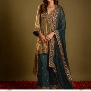 Zareen Teal & Gold Designer Palazzo Suit by Maharani Designer Boutique Make an elegant statement with the Zareen Teal & Gold Embroidered Palazzo Suit, a sophisticated three-piece ethnic ensemble from Maharani Designer Boutique. Designed around a rich deep teal-blue and antique-gold colour combination, this outfit brings together traditional Indian embroidery, a graceful long kurta, coordinated wide-leg pants and a beautifully bordered dupatta. The colour palette is the first thing that makes this ensemble distinctive. The deep teal-blue lower and dupatta sections create a dramatic foundation, while the warm gold-toned kurta and embroidery add richness and sophistication. The combination feels luxurious without relying on an overly bright colour palette, making it an excellent choice for women who prefer elegant, mature and timeless occasion wear. Teal Blue & Gold Embroidered Palazzo Suit with Dupatta The kurta features an ornate neckline with concentrated embroidery extending across the upper front. Decorative embroidery also appears along the sleeve cuffs and lower hem, creating a balanced relationship between the different parts of the outfit. The teal-blue palazzo pants are finished with delicate gold motifs and an elaborate embroidered border, while the matching teal dupatta features a richly decorated edge that frames the complete ensemble. Zareen is designed for women looking for a designer Punjabi suit, teal blue palazzo suit, gold embroidered suit, party wear Punjabi suit, wedding guest outfit, or an elegant ethnic ensemble for festive and formal occasions. A Rich Teal and Gold Colour Combination The defining characteristic of Zareen is its sophisticated teal-blue and gold colour story. Deep teal is a striking alternative to more traditional festive shades such as red, maroon or emerald. It provides depth and character while remaining remarkably versatile. The gold elements add warmth and traditional richness. Together, teal and gold create a colour combination that works particularly well for evening celebrations, wedding functions and formal gatherings. The gold detailing catches attention against the darker teal sections, while the warm champagne-gold tone of the kurta keeps the overall look harmonious. This is an ensemble that can easily be styled according to the occasion. For a subtle daytime appearance, pair it with minimal jewellery and understated footwear. For an evening celebration, introduce statement earrings, bangles and embellished footwear to enhance its luxurious character. Elegant Embroidered Kurta The kurta forms the centrepiece of the outfit. It features a long, elegant silhouette in a warm gold-toned shade. The elongated shape creates a graceful vertical line and complements the wider silhouette of the coordinated palazzo pants. The neckline is one of the most detailed areas of the garment. Ornamental embroidery frames the neckline and extends downward across the front, creating a decorative focal point. The embroidery incorporates floral and traditional-inspired patterns, giving the kurta a distinctly festive appearance. Small decorative motifs are distributed across the body, preventing the design from feeling visually heavy. The lower hem features another concentrated embroidered border, creating a polished finishing detail. Statement Neckline The neckline has been designed as a focal point. A decorative U-shaped opening is surrounded by intricate gold-toned embroidery. Additional ornamental detailing extends across the upper chest area, giving the outfit a refined couture-inspired appearance. This neckline works beautifully with traditional jewellery. A delicate necklace can emphasize the central embroidery, while statement earrings can provide an elegant alternative for those who prefer not to wear a necklace. The vertical placement of the embroidery also complements the long silhouette of the kurta. Intricate Gold Embroidery The embroidery throughout Zareen is designed to provide richness and dimension. The gold detailing contrasts beautifully with both the warm kurta and deep teal components. Floral-inspired motifs, ornamental borders and small decorative elements create a layered visual effect. The embroidery is particularly concentrated around: The neckline Upper front of the kurta Sleeve cuffs Kurta hem Palazzo hem Dupatta border This placement creates a sense of coordination across the entire three-piece ensemble. Rather than treating each garment as an independent piece, the embroidery visually connects the kurta, palazzo and dupatta. Beautiful Sleeve Detailing The sleeves feature an elegant flared shape with richly decorated cuffs. The gold embroidery around the cuffs adds a traditional element while maintaining the contemporary silhouette. The wider cuff creates a graceful movement around the wrists and works beautifully with bangles. For a traditional styling approach, wear several slim bangles. For a modern appearance, a single statement bracelet or cuff can provide a cleaner look. The sleeve design ensures that the outfit remains visually interesting even when the dupatta is removed or repositioned. Teal Blue Palazzo Pants The coordinated teal-blue palazzo pants introduce a contemporary dimension to the ensemble. Their wide-leg silhouette provides fluid movement and creates a relaxed yet elegant appearance. The deep teal shade provides a beautiful contrast to the warm gold kurta. Small gold motifs are distributed across the palazzo, giving the lower section subtle decorative detail. The bottom edge features an elaborate embroidered border that adds definition and visually connects the pants with the embroidery on the kurta. The wide-leg design also provides a modern alternative to traditional narrow Punjabi trousers. Embroidered Palazzo Border The lower border of the palazzo is one of its most distinctive details. Rich gold-toned embroidery creates a decorative frame around the bottom edge. The border features floral and ornamental motifs, adding visual weight to the lower silhouette. This detail becomes especially noticeable when the wearer walks or moves, allowing the embroidery to catch the light. The border also creates a visual connection with the embroidered hem of the kurta. Together, these details create a coordinated and balanced appearance from top to bottom. Rich Teal Dupatta The matching teal dupatta completes the outfit. Its deep colour creates a sophisticated contrast against the warm gold kurta. The dupatta is finished with a prominent embroidered border that runs along its edges. This border introduces the same decorative language found throughout the rest of the outfit. The dupatta can be styled in several ways depending on your personal preference. Drape it over one shoulder for a contemporary appearance, carry it across both shoulders for a more traditional silhouette, or allow the embroidered border to fall vertically at the front for a dramatic evening look. Statement Dupatta Border The elaborate dupatta border gives the ensemble much of its formal character. Gold-toned floral and ornamental embroidery frames the teal fabric, creating a striking contrast. When the dupatta is draped over one shoulder, the embroidered border becomes a strong vertical feature. This can visually elongate the outfit and draw attention toward the intricate craftsmanship. The dupatta can also be used to create different styling moods. A loose drape feels modern and relaxed. A carefully pleated drape feels polished and formal. A traditional head drape creates a more classic ethnic appearance. Perfect Wedding Guest Outfit Zareen makes a sophisticated choice for women attending weddings and other formal celebrations. Its deep teal colour allows you to stand apart from more conventional festive shades while retaining a distinctly Indian aesthetic. The outfit can be worn for: Wedding receptions Engagement ceremonies Sangeet events Mehndi celebrations Family weddings Festive dinners Anniversary celebrations Formal parties Cultural events Religious or traditional gatherings Because the colour combination is sophisticated rather than extremely bright, it can transition easily between different types of occasions. Wedding Reception Styling For a wedding reception, style Zareen with statement jewellery. Gold-toned earrings, a delicate choker and stacked bangles can complement the embroidery beautifully. Choose metallic or embellished footwear to complete the look. For the dupatta, use a one-shoulder drape and allow the decorated border to fall naturally. A soft updo or loose waves can finish the ensemble. Engagement Party Look For an engagement celebration, keep the styling refined. Choose statement earrings with a delicate bracelet and minimal additional jewellery. The detailed neckline already creates a focal point, so a heavy necklace is optional. Pair the outfit with metallic heels and a compact clutch. Soft glowing makeup, defined eyes and a neutral or warm-toned lip can complement the gold and teal colour palette. Sangeet Outfit Zareen can also be styled beautifully for a sangeet. The wide-leg palazzo silhouette offers natural movement, while the teal colour creates an elegant evening appearance. For a festive sangeet look, consider: Gold statement earrings Layered bangles Embellished heels Decorative clutch Soft curls Bold eye makeup Keep the dupatta draped over one shoulder so that the palazzo and kurta remain clearly visible. Mehndi Function Styling For a mehndi function, add colourful accessories to introduce a playful element. You can pair the teal and gold outfit with contrasting bangles, colourful earrings or embellished Punjabi juttis. Floral jewellery can also provide a fresh contrast against the darker teal colour. A braided hairstyle decorated with flowers can give the ensemble a more traditional appearance. Festive Wear Zareen is not limited to weddings. The sophisticated colour combination makes it suitable for festive celebrations, family gatherings and special dinners. During festivals, pair it with traditional jewellery and comfortable ethnic footwear. For smaller gatherings, simplify the accessories and let the embroidery remain the primary decorative feature. This flexibility makes the outfit a valuable addition to an occasion-wear wardrobe. Jewellery Styling Guide The teal and gold colour combination works beautifully with several jewellery styles. Gold Jewellery Gold is the natural choice for this outfit. It complements both the warm kurta and gold embroidery. Kundan-Inspired Jewellery Kundan-inspired pieces can create a traditional bridal-adjacent appearance without requiring a full bridal ensemble. Pearl Jewellery Pearls can soften the richness of the teal and gold palette. Jhumkas Classic jhumkas provide an effortless Indian finishing touch. Choker A refined choker can emphasize the neckline. Bangles Stacked bangles add movement and reinforce the traditional character of the ensemble. Footwear Suggestions The wide-leg palazzo silhouette works particularly well with elevated footwear. For traditional events, consider embellished Punjabi juttis or mojaris. For formal evening functions, metallic sandals or heels can create a more glamorous finish. Gold footwear naturally complements the embroidery. Neutral footwear can provide a quieter styling option. If you expect to wear the outfit for several hours, choose footwear that provides sufficient comfort and stability. Dupatta Draping Options One-Shoulder Drape Place the dupatta over one shoulder and let the embroidered border fall vertically. This creates a contemporary and elegant appearance. Both-Shoulder Drape Drape the dupatta across both shoulders for a more symmetrical and traditional look. Front Drape Bring the dupatta across the front to create a modest and classic silhouette. Head Drape For traditional ceremonies, the dupatta can be gently placed over the head. Relaxed Drape Allow the dupatta to fall naturally from one shoulder for an effortless designer look. Hairstyle Ideas The outfit works with both traditional and contemporary hairstyles. Soft Waves Loose waves create a feminine evening appearance. Low Bun A sleek low bun highlights the neckline and embroidery. Side-Swept Hair Side-swept waves can emphasize statement earrings. Braided Hairstyle A decorated braid complements the ethnic character of the outfit. Sleek Ponytail A polished ponytail offers a contemporary contrast to the traditional embroidery. Makeup Inspiration The warm gold and deep teal combination allows for sophisticated makeup choices. For daytime celebrations, choose luminous skin, soft brown eye makeup, defined lashes and a nude or warm-toned lip. For evening functions, introduce stronger eyeliner, a glowing complexion and a richer rose or neutral lip. Gold-toned highlighter can complement the embroidery, while warm blush tones can harmonize with the overall palette. The goal is to enhance the outfit's richness without overpowering its detailed embroidery. Contemporary Punjabi Fashion Zareen represents a modern approach to Punjabi-inspired ethnic wear. The outfit combines traditional decorative elements with a contemporary silhouette. The long kurta provides classic elegance. The wide-leg palazzo introduces modern proportions. The teal and gold palette provides a sophisticated alternative to conventional festive colours. The embroidered dupatta adds the traditional finishing layer expected from an occasion-wear ensemble. This combination makes the outfit appropriate for women who want cultural elegance with a contemporary fashion sensibility. A Versatile Three-Piece Ensemble The three-piece construction makes Zareen particularly versatile. The kurta and palazzo create a complete look even without the dupatta. The dupatta can be styled with other coordinated ethnic outfits in your wardrobe. The teal palazzo can potentially be paired with a contrasting embroidered kurta for a different appearance. The gold kurta can also work with complementary trousers or palazzos depending on personal styling. This allows the ensemble to provide multiple styling possibilities beyond a single event. Day-to-Evening Styling Zareen can easily be adapted from a sophisticated daytime outfit into evening occasion wear. Daytime Look Choose minimal jewellery, simple footwear and soft makeup. Evening Look Add statement earrings, bangles, heels and an embellished clutch. Formal Look Choose a refined choker, polished hairstyle and carefully pleated dupatta. The deep teal colour provides a strong foundation for all three styling directions. Why Choose Zareen? Zareen is ideal for women searching for: A sophisticated teal-blue Punjabi suit A gold embroidered palazzo suit A designer ethnic outfit A wedding guest suit A party wear Punjabi suit A festive three-piece ensemble A teal and gold ethnic outfit A contemporary sharara-inspired silhouette An embroidered suit with dupatta An elegant outfit from Maharani Designer Boutique It combines colour, embroidery and silhouette to create a memorable occasion-wear look. Maharani Designer Boutique Maharani Designer Boutique presents elegant ethnic fashion designed around sophisticated colour combinations, detailed embellishment and contemporary interpretations of traditional silhouettes. Zareen reflects this aesthetic through its combination of deep teal, warm gold, decorative embroidery and flowing proportions. The outfit is designed to make the wearer feel polished and occasion-ready while providing enough versatility for different celebrations. Whether you're dressing for a wedding reception, engagement, sangeet, festive dinner or family celebration, Zareen offers an elegant alternative to conventional bright-coloured occasion wear. Product Details Product Name: Zareen Teal & Gold Embroidered Palazzo Suit Brand: Maharani Designer Boutique Category: Designer Palazzo Suit / Punjabi Suit Primary Colours: Teal Blue and Warm Gold Dupatta Colour: Deep Teal Blue Kurta: Long gold-toned embroidered kurta Bottom: Wide-leg teal palazzo pants with gold motifs and embroidered border Dupatta: Teal dupatta with elaborate embroidered border Design: Floral and ornamental-inspired embroidery Style: Contemporary Ethnic / Punjabi-Inspired Occasion Wear Occasions: Weddings, Receptions, Engagements, Mehndi, Sangeet, Festive Celebrations, Parties and Family Functions Exact fabric composition, measurements, lining, embroidery technique and customization availability should be confirmed with Maharani Designer Boutique before ordering, as these specifications cannot be reliably determined from the product image alone. Royal Blue Embroidered , Royal Teal Hand Embroidered Kurta Palazzo Suit, Ivory Gold Heritage Embroidered Bridal Lehenga Choli, Maroon Bridal Sharara Suit with Gold Embroidery, Gold Embroidered Sharara Suit with Peach Dupatta Care & Storage As an occasion-wear ensemble featuring decorative embroidery, Zareen should be handled carefully. Store the outfit in a clean garment bag in a dry environment. Avoid exposing the embroidered areas to rough surfaces or sharp jewellery that could catch the decorative work. Keep perfumes, oils and cosmetic products away from the fabric. Follow the actual garment's care label for cleaning instructions. Professional cleaning may be appropriate depending on the final fabric and embellishment. Store the dupatta carefully so its embroidered border does not become crushed beneath heavier garments. When transporting the outfit, fold each component carefully and avoid placing heavy objects directly over the embroidery. Proper care can help preserve the appearance and decorative detailing of the ensemble for future celebrations. teal Punjabi suit, teal blue Punjabi suit, teal Punjabi suit for women, teal blue suit for women, teal and gold Punjabi suit, teal gold suit, teal palazzo suit, teal palazzo suit for women, teal embroidered suit, teal embroidered Punjabi suit, gold embroidered Punjabi suit, designer Punjabi suit, designer Punjabi suits online, designer palazzo suit, designer palazzo suit for women, embroidered palazzo suit, embroidered palazzo suit for women, Punjabi suit online, Punjabi suits online, Punjabi suit for wedding, Punjabi suit for wedding guest, wedding guest Punjabi suit, wedding guest outfit for women, teal wedding guest outfit, teal suit for wedding, gold suit for wedding, party wear Punjabi suit, teal party wear suit, gold party wear suit, designer party wear suit, ethnic party wear suit, Indian ethnic wear for women, Indian designer suit, designer ethnic wear,embroidered ethnic wear