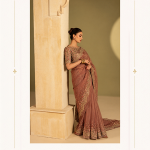 Dusty Mauve Designer Embroidered Saree with Heavy Border Make a graceful statement with the Maharani Mauve Royal Embroidered Saree, an elegant designer saree crafted for women who love sophisticated ethnic fashion. Featuring a rich dusty mauve-brown shade, this saree is beautifully adorned with intricate golden embroidery and delicate embellishments throughout. The saree showcases an ornate embroidered border with floral and traditional motifs, adding a luxurious finish to its flowing silhouette. Scattered embellishments across the drape create a subtle shimmer, while the beautifully detailed pallu enhances the overall grandeur of the ensemble. Maharani Mauve Royal Embroidered Saree The coordinating blouse features exquisite embroidery with intricate floral detailing, perfectly complementing the saree. Its elegant short-sleeve design adds a contemporary touch while maintaining the timeless appeal of traditional Indian fashion. Perfect for weddings, receptions, engagement ceremonies, festive celebrations, parties, family functions, and elegant evening occasions, this designer saree is a beautiful choice for creating a sophisticated and memorable look. Maharani Mauve Royal Embroidered Saree dusty mauve saree, mauve embroidered saree, dusty pink saree, brown pink saree, designer saree, embroidered designer saree, wedding saree for women, wedding wear saree, party wear saree, reception saree, engagement saree, festive saree, luxury saree, heavy embroidered saree, designer wedding saree, saree with embroidered blouse, Maharani Designer Boutique Jalandhar Designed by Maharani Designer Boutique, this saree combines traditional Indian elegance with modern designer styling. Pair it with statement earrings, bangles, embellished heels, and a clutch to complete your occasion-ready look. Royal Dusty Mauve,Dusty Rose Embroidered ,Embroidered Punjabi Suit ,Maharani Rose Gold Embroidered,Dusty Rose Pink Embroidered  Maharani Designer Boutique, Maharani Designer, Maharani Boutique, designer boutique Jalandhar, saree boutique Jalandhar, designer sarees Jalandhar, wedding sarees Jalandhar, Punjabi boutique Jalandhar