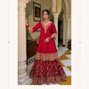 Ruby Red Embroidered Sharara Suit with Long Kurta & Dupatta by Maharani Designer Boutique Make a memorable entrance at your next celebration with the Ruby Red Embroidered Sharara Suit with Long Kurta & Dupatta, a statement-making Indian ethnic ensemble designed for women who love rich colours, graceful silhouettes and traditional-inspired embroidery. Created under the aesthetic of Maharani Designer Boutique, this striking red outfit brings together a beautifully embellished long kurta, dramatically flared sharara trousers and a coordinated dupatta for a complete festive look. The deep ruby-red colour gives this ensemble a bold and luxurious presence. Gold-toned embroidery creates an elegant contrast against the red base, highlighting the neckline, sleeve cuffs, kurta hem and flowing sharara. The overall design balances statement detailing with a graceful silhouette, making it an excellent choice for weddings, festive celebrations, family functions, receptions, engagement ceremonies and other special occasions. The upper kurta features a flattering V-shaped neckline with elaborate ornamental embroidery flowing down toward the centre. The long sleeves are finished with wide embroidered cuffs that add richness to the overall appearance. The kurta falls gracefully over the upper portion of the sharara and is finished with layered decorative borders. The sharara underneath introduces volume and movement. Its wide flare is covered with intricate vertical and floral-inspired patterns, while multiple borders at the hem create a rich finishing effect. Together, the kurta and sharara create a traditional yet contemporary silhouette that feels festive, feminine and elegant. Rich Ruby Red Colour The defining visual characteristic of this ensemble is its rich ruby-red colour. Red has long held an important place in Indian occasion wear, particularly for celebrations, weddings and festive gatherings. In this design, the deep red foundation creates a dramatic canvas for the gold-toned embroidery. The combination feels regal without requiring additional bright colours. The richness of the red allows the intricate embroidery to stand out beautifully. When paired with traditional gold jewellery, the outfit takes on a classic festive appearance. For a more contemporary styling approach, it can be paired with minimal jewellery and elegant heels. This versatile colour also makes the ensemble suitable for both daytime and evening celebrations. Elegant Long Kurta The long kurta is designed with a flowing silhouette that provides coverage while maintaining a graceful shape. Its upper portion features detailed embroidery around the neckline and chest area. The embroidery forms a decorative central motif that naturally draws attention toward the face. The V-shaped neckline gives the kurta a contemporary touch while retaining its traditional character. Small decorative motifs extend across the red fabric, creating visual continuity between the neckline and lower sections. The kurta length creates a beautiful transition into the heavily embellished sharara beneath. Statement Embroidered Neckline The neckline is one of the most prominent details of this designer suit. Gold-toned embroidery surrounds the V-shaped neckline and extends downward in a decorative arrangement. The central motif resembles traditional ornamental and floral-inspired artwork, giving the neckline a luxurious appearance. This detailing makes the outfit particularly suitable for statement jewellery. A traditional choker can be worn with the neckline for a classic wedding look, while long earrings alone can create a more contemporary appearance. Elaborately Embroidered Sleeves The full-length sleeves provide an elegant and refined appearance. The main sleeve area maintains the red base while the cuffs feature concentrated embroidery. The wide embroidered cuffs provide a strong finishing detail and coordinate visually with the kurta's lower borders. They also create an attractive frame around the wrists, making bangles and traditional bracelets especially effective accessories. For wedding styling, stack gold or red bangles around the cuffs. For a modern look, wear one statement bracelet or keep the wrists minimal. Ornate Kurta Border The lower portion of the kurta features multiple embroidered borders. The layered border creates definition between the upper kurta and the voluminous sharara. The embroidery includes traditional ornamental patterns and floral-inspired motifs that repeat throughout the ensemble. This creates a cohesive appearance and ensures that the kurta does not look visually disconnected from the bottom. Dramatic Sharara Silhouette The sharara is the defining silhouette of this ensemble. Its wide flare creates dramatic volume and beautiful movement. Unlike narrow trousers, the sharara opens gradually into a broad, flowing shape, giving the outfit a festive and traditional character. The wide-leg design also makes the ensemble particularly attractive for celebrations where movement is part of the occasion. As the wearer walks, the embroidered panels move naturally, allowing the decorative patterns to become more visible. Intricate Sharara Embroidery The red sharara features elaborate gold-toned embroidery distributed throughout its length. Vertical ornamental patterns create an elongated visual effect, while floral and decorative motifs add richness. The lower section becomes increasingly detailed toward the hem, creating a strong visual foundation. Multiple embroidered borders complete the bottom edge. This concentration of embroidery at the hem gives the sharara a luxurious finish and enhances its dramatic flare. Layered Embroidered Borders The multiple borders at the bottom of the sharara are among the strongest design details. They incorporate different ornamental patterns and create a layered appearance. The borders provide structure to the wide silhouette while maintaining the flowing quality of the fabric. This detailing also gives the ensemble a traditional Indian festive character. Coordinated Dupatta The matching red dupatta completes the outfit. It features delicate scattered embellishment and an ornate border that coordinates with the kurta and sharara. The dupatta adds another flowing layer to the silhouette. It can be draped across one shoulder, placed over both shoulders or styled in a more traditional manner. The embroidered border becomes a prominent feature when the dupatta is worn over one shoulder. Traditional Dupatta Styling For a classic ethnic look, drape the dupatta across both shoulders and allow the embroidered edges to fall naturally. For a more contemporary look, place it over one shoulder and let the border fall vertically. For wedding ceremonies, the dupatta can also be styled over the head. The deep red shade allows the dupatta to become an important part of the overall styling rather than simply serving as an accessory. Designer Sharara Suit for Weddings The Ruhani Riwaaz Sharara Suit is an excellent choice for wedding celebrations. Its rich red colour, detailed embroidery and flowing silhouette make it appropriate for important occasions such as: Wedding functions Engagement ceremonies Sangeet nights Mehndi celebrations Wedding receptions Family ceremonies Festive gatherings Formal dinners Traditional celebrations For a wedding guest look, pair it with elegant gold jewellery and an embellished clutch. Perfect for Mehndi Functions The vibrant red colour and flowing sharara silhouette make this ensemble a beautiful option for mehndi celebrations. Mehndi events often encourage colourful and expressive ethnic styling. Pair this suit with: Gold jhumkas Red and gold bangles Embellished Punjabi juttis A traditional potli Soft curls or a braided hairstyle A small floral hair accessory can also complement the festive mood. Sangeet Ready Style The sharara silhouette is particularly suited to sangeet celebrations. Its broad flare creates movement, making it an attractive option for an evening filled with music, dancing and celebration. Style the outfit with statement earrings and comfortable block heels. A sleek updo or soft waves can complete the look. For a more dramatic appearance, add a traditional maang tikka. Reception Wear for Women For a wedding reception, this red designer sharara can be styled in a more glamorous way. Choose statement earrings, a refined choker, embellished heels and a metallic clutch. A polished bun or elegant waves can create a sophisticated evening appearance. Keep the makeup luminous with defined eyes and a warm lip shade. Festive Indian Ethnic Wear The Ruhani Riwaaz Sharara Suit is not limited to weddings. It can also be worn for a variety of festive occasions. Consider styling it for: Diwali: Pair it with gold jewellery and embellished footwear. Karwa Chauth: Add traditional bangles, a bindi and statement earrings. Lohri: Choose bold jewellery and Punjabi-inspired accessories. Family Celebrations: Keep jewellery refined for a sophisticated appearance. Festive Dinner: Use minimal jewellery and a contemporary clutch for a modern ethnic look. Designer Sharara Suit for Women Sharara suits have become a popular choice for women seeking an alternative to traditional salwar suits and lehengas. They combine the comfort of trousers with the volume and visual drama associated with traditional Indian festive wear. This ensemble takes that silhouette further through elaborate embroidery and a coordinated long kurta. The result is an outfit that feels traditional while still fitting comfortably into contemporary ethnic fashion. Jewellery Styling Guide The ruby-red and gold combination makes jewellery styling simple and versatile. Gold Choker A traditional gold choker can beautifully frame the embroidered neckline. Jhumka Earrings Gold jhumkas provide a classic Punjabi-inspired appearance. Chandbali Earrings Chandbalis can add a more statement-oriented festive touch. Maang Tikka A maang tikka can enhance the traditional wedding aesthetic. Bangles Red, gold and green bangles can create a classic Indian combination. Statement Ring A large traditional ring adds a finishing detail without overwhelming the outfit. Footwear Recommendations Because the sharara has a broad and flowing silhouette, footwear with a little elevation can complement the proportions. Suitable choices include: Gold heels Embellished sandals Metallic block heels Traditional Punjabi juttis Embroidered mojaris Nude heels Gold wedges For dancing and long celebrations, block heels or embellished flats can offer a practical alternative to high stilettos. Clutch & Potli Suggestions A traditional embroidered potli is an excellent match for this ensemble. Choose gold, red, champagne or neutral tones. For a more contemporary appearance, select a structured metallic clutch. Avoid overly bright contrasting accessories because the ruby-red and gold combination already creates a strong visual statement. Hairstyle Ideas Traditional Bun A sleek bun creates a classic wedding-ready appearance. Low Chignon A low chignon gives the outfit an elegant and sophisticated finish. Soft Waves Loose waves offer a more relaxed and contemporary look. Braided Hairstyle A traditional braid can reinforce the Punjabi-inspired character of the outfit. Floral Bun Flowers added to a traditional bun can create a beautiful festive look. Makeup Ideas The deep red colour works particularly well with warm and neutral makeup tones. For daytime functions, consider soft brown eyeshadow, defined brows, peach blush and a nude or warm-toned lip. For evening celebrations, stronger eye makeup, glowing skin and a deeper lip colour can create a more dramatic appearance. Gold or bronze eyeshadow can coordinate naturally with the embroidery. Modern Styling Option Although this is a traditional-inspired outfit, it can easily be styled in a contemporary way. Wear the dupatta over one shoulder. Choose statement earrings instead of a heavy necklace. Style your hair in loose waves. Complete the look with metallic heels and a structured clutch. This creates an elegant fusion appearance while allowing the embroidery and sharara silhouette to remain the focus. Traditional Punjabi Styling For a more traditional Punjabi look, wear the dupatta across both shoulders. Add gold jhumkas, red-and-gold bangles, a maang tikka and Punjabi juttis. A traditional braided hairstyle can further enhance the ethnic character. This styling approach works particularly well for mehndi, family weddings and cultural celebrations. Why Choose This Ruby Red Sharara Suit? Rich Ruby-Red Colour Creates a bold and luxurious festive appearance. Gold-Toned Embroidery Adds traditional richness and visual depth. Long Embroidered Kurta Provides an elegant and graceful silhouette. Wide Sharara Creates dramatic movement and volume. Ornate Borders Give the outfit a beautifully finished appearance. Coordinated Dupatta Completes the ensemble and offers multiple styling options. Versatile Occasion Wear Suitable for weddings, receptions, engagements, festive events and family celebrations. An Outfit Designed for Special Moments Some outfits are made for everyday occasions, while others are designed to become part of memorable moments. The Ruhani Riwaaz Ruby Red Sharara Suit belongs to the second category. Its rich colour and detailed embroidery make it appropriate for occasions where you want your ethnic outfit to feel special. Whether you are attending a close family wedding, celebrating an engagement or dressing up for a festive evening, the ensemble offers an elegant and confident appearance. A Beautiful Choice for Wedding Guests If you are searching for a wedding guest sharara suit, this design offers a sophisticated option. The ruby-red colour provides a strong festive presence, while the long kurta creates a graceful silhouette. Unlike a traditional bridal lehenga, the sharara suit can provide a slightly more versatile and comfortable styling option for guests. Pair it with elegant accessories to create a polished wedding look. Occasion-Wear Investment A richly embroidered sharara can become a valuable addition to an ethnic wardrobe because it can be styled in several different ways. The same outfit can appear traditional with heavy jewellery or contemporary with minimal accessories. Change the hairstyle, footwear, jewellery and dupatta drape to create a new appearance for different celebrations. This versatility allows you to get more styling possibilities from a single designer ensemble. Maharani Designer Boutique Maharani Designer Boutique represents elegant Indian ethnic fashion with an emphasis on occasion-ready silhouettes, decorative detailing and timeless colour combinations. The Ruhani Riwaaz Ruby Red Sharara Suit reflects this aesthetic through its rich red colour, elaborate gold-toned embroidery, flowing sharara silhouette and coordinated dupatta. It is designed for women who want to celebrate traditional Indian fashion while maintaining a polished contemporary appearance. Product Details Product Name: Ruhani Riwaaz Ruby Red Embroidered Sharara Suit Brand: Maharani Designer Boutique Category: Designer Sharara Suit Colour: Ruby Red / Deep Red with Gold-Toned Detailing Top: Long embroidered kurta Bottom: Wide-flare embroidered sharara Dupatta: Coordinated red dupatta with decorative embroidered border Neckline: V-shaped embroidered neckline Sleeves: Full-length sleeves with embellished cuffs Style: Indian Ethnic / Punjabi-Inspired Occasion Wear Occasions: Wedding, Reception, Engagement, Mehndi, Sangeet, Festive Wear and Family Celebrations Product note: Exact fabric composition, lining, measurements, embroidery technique, embellishment materials and stitching/customization options should be confirmed with Maharani Designer Boutique before purchase, as these specifications cannot be reliably determined from the product image alone. Care Instructions To maintain the appearance of a detailed designer ethnic outfit, careful handling is recommended. Store the suit in a clean, breathable garment bag when not being worn. Keep it away from excessive moisture, direct sunlight and harsh environmental conditions. Avoid spraying perfume directly onto the fabric or embroidered areas. Take care while wearing jewellery, watches or accessories that could catch on embroidery. After wearing, allow the outfit to air before placing it into long-term storage. Follow the specific care instructions provided with the finished garment. Depending on the actual fabric and embellishment used, professional cleaning may be recommended. Fold the embroidered dupatta carefully and avoid placing heavy items on top of it. Final Product Description The Ruhani Riwaaz Ruby Red Embroidered Sharara Suit is a celebration of rich colour, graceful movement and traditional-inspired Indian craftsmanship. Its deep ruby-red foundation creates a powerful visual statement, while gold-toned embroidery adds an elegant layer of richness. The beautifully detailed neckline draws attention toward the face, while the embroidered sleeve cuffs add sophistication to the long kurta. The wide sharara creates the drama and movement expected from festive Indian occasion wear. Elaborate embroidery extends across the flared trousers, becoming more detailed toward the lower borders and creating a luxurious finishing effect. The coordinated red dupatta completes the ensemble with delicate embellishment and a beautifully decorated border. It can be styled traditionally across both shoulders, casually over one shoulder or in a more ceremonial manner for special occasions. From weddings and receptions to mehndi celebrations, sangeet nights, engagement parties and festive family gatherings, this designer sharara suit provides an elegant and versatile styling option. Pair it with traditional gold jewellery, bangles and Punjabi juttis for a classic ethnic appearance. Alternatively, style it with statement earrings, metallic heels and a contemporary clutch for a modern festive look. With its striking ruby-red colour, elaborate gold-toned detailing and flowing sharara silhouette, the Ruhani Riwaaz Sharara Suit by Maharani Designer Boutique is created to make special occasions feel even more memorable. Celebrate your most beautiful moments in elegant Indian ethnic wear from Maharani Designer Boutique, where traditional inspiration meets sophisticated contemporary styling. red sharara suit, ruby red sharara suit, red sharara suit for women, designer sharara suit, embroidered sharara suit, Punjabi sharara suit, Punjabi suit for wedding, red Punjabi suit, red wedding suit for women, designer Punjabi suit, Punjabi wedding wear, Punjabi party wear suit, sharara suit for wedding, sharara suit for mehndi, sharara suit for sangeet, red ethnic wear for women, embroidered ethnic wear, designer ethnic wear, wedding guest sharara suit, red party wear suit, festive sharara suit, Indian wedding outfit for women, traditional sharara suit, embroidered Punjabi suit, red salwar suit, designer salwar suit, Maharani Designer Boutique, Maharani Designer, Punjabi suit boutique, designer suit boutique.