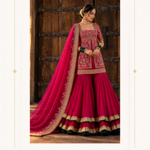 Maharani Royal Magenta Heritage Embroidered Sharara Suit Make a statement at every celebration with the Maharani Royal Magenta Heritage Embroidered Sharara Suit, Magenta Pink Designer Sharara Suit with Intricate Gold Embroidery, Maharani Designer Boutique , a luxurious ensemble that beautifully blends traditional Indian craftsmanship with regal elegance. Designed in a rich magenta pink shade, this designer sharara suit features intricate gold-toned embroidery across the fitted kurta, creating a sophisticated and festive look. The flowing sharara pants feature layered gathers and striking gold borders that add graceful volume and movement. A matching dupatta, adorned with delicate embellishments and an ornate embroidered border, completes this stunning traditional outfit. Perfect for weddings, festive celebrations, engagement ceremonies, sangeet nights, and family occasions, this designer Punjabi outfit is ideal for women who appreciate timeless ethnic fashion with a luxurious finish. Product Highlights Colour: Royal Magenta Pink Style: Designer Sharara Suit Work: Intricate gold-toned embroidery Kurta: Embellished design with a statement hem Bottom: Flared sharara with layered gold borders Dupatta: Matching dupatta with an embroidered border